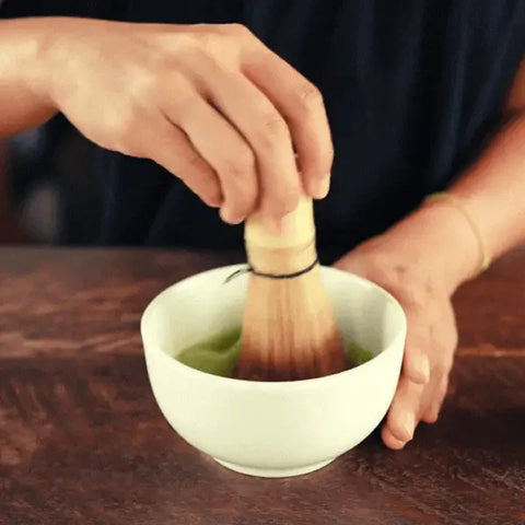 Batir té matcha con chasen en un cuenco.