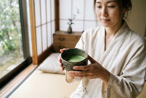 persona sosteniendo un cuenco de matcha en un entorno japonés minimalista con luz natural
