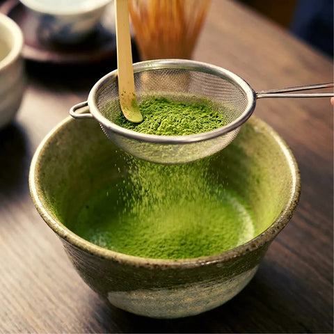 Tamizando té matcha en polvo sobre un cuenco.